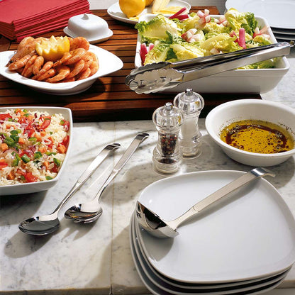 Ein Buffet mit gestapelten weißen Tellern, dem Amefa BUFFET Wender/Heber, Salat, Garnelen, Reissalat, Kräuterolivenöl, Salz- und Pfefferstreuer und roten Servietten auf einer Marmorplatte.